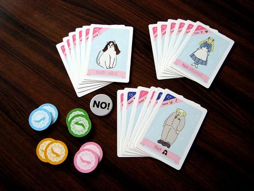 Three piles of cards, one with a feminine cat on top, one with a feminine human, and one with a masculine human. There is also a token that says 'NO!' in large letters.